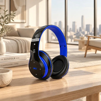 Blue and black wireless over-ear headphones displayed on a wooden table in a modern living room setting.
