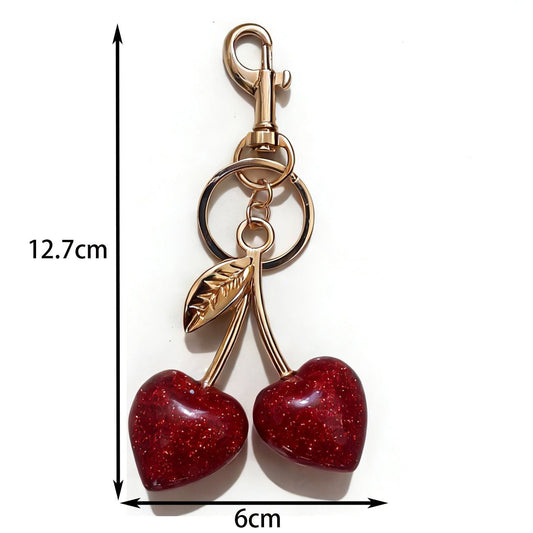 Gold keychain with red heart-shaped charms and measurements on a white background