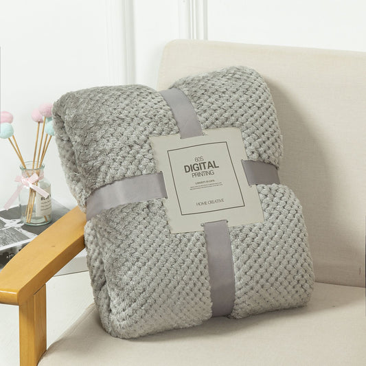 Gray textured blanket with a tag on a beige couch