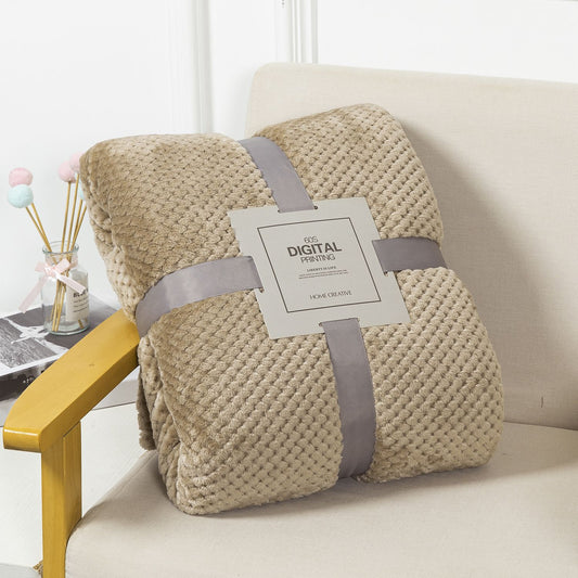 Beige textured blanket with a tag on a white sofa